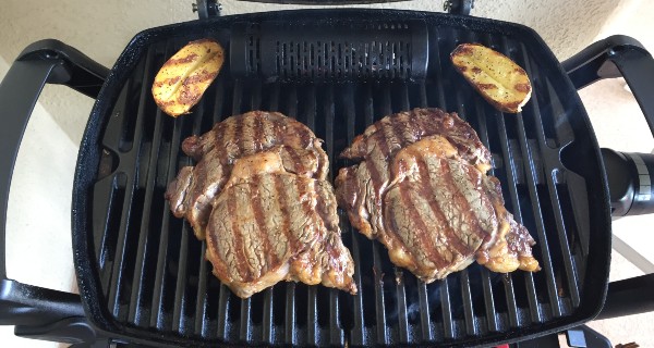 Grill steak on an electric stove. Pork neck fried on small electric grill.  Home cooking. Healthy barbecue. Catering to friends. Electric grilling.  Stock Photo